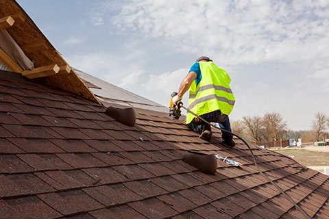 man on roof patching up hail roof damage in Monument